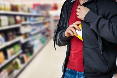 Une figure masculine sur le point de dissimuler un article sous sa veste